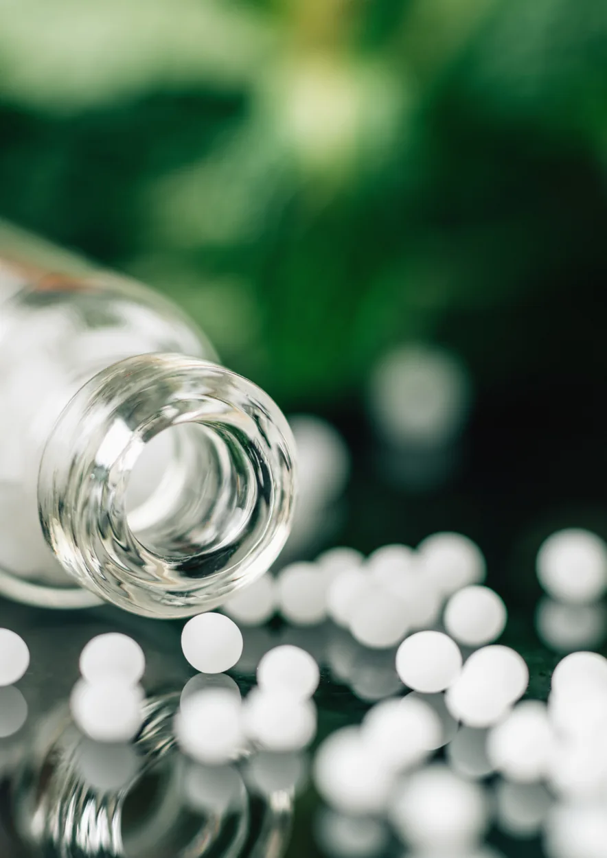 Homeopathic remedy bottle with small white tablets on a botanical green surface