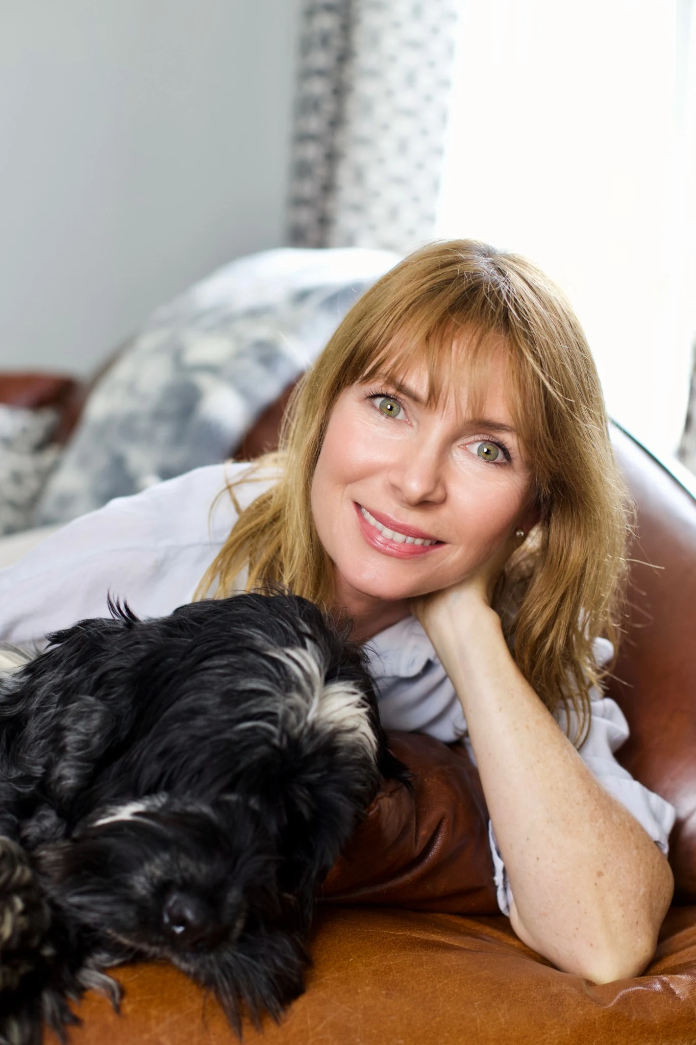Susan smiling warmly while relaxing at home with her dog