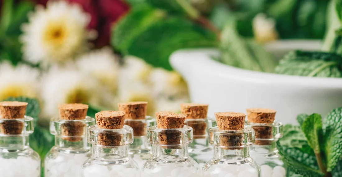 Homeopathic remedy bottles amongst fresh plants and flowers